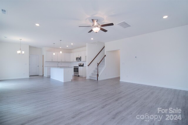 unfurnished living room with light wood-type flooring, sink, and ceiling fan with notable chandelier