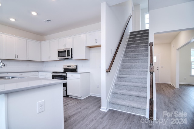 kitchen with white cabinets, light wood-type flooring, and stainless steel appliances