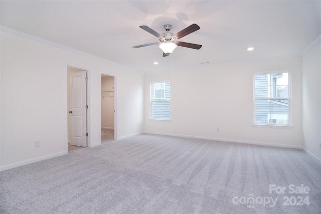 spare room with ceiling fan, light colored carpet, and crown molding