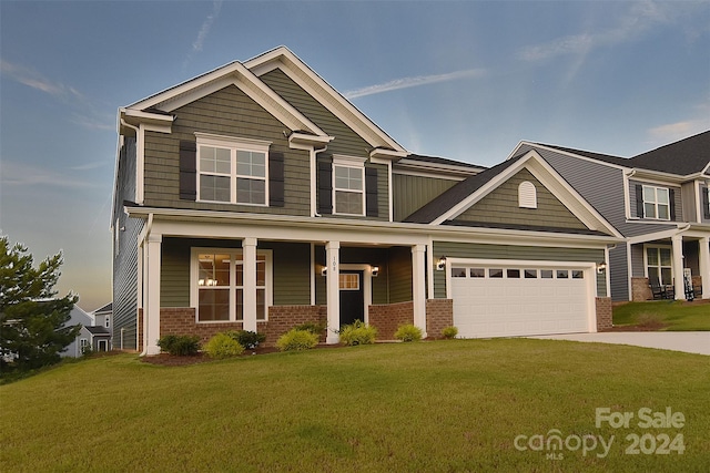 craftsman-style home featuring a front yard, covered porch, and a garage