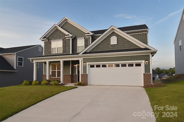 craftsman house with driveway, an attached garage, a front yard, a porch, and brick siding