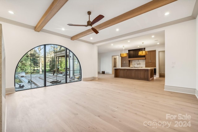 unfurnished living room featuring beamed ceiling, light hardwood / wood-style flooring, and ceiling fan