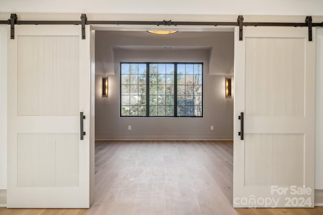 empty room with a barn door and light hardwood / wood-style floors