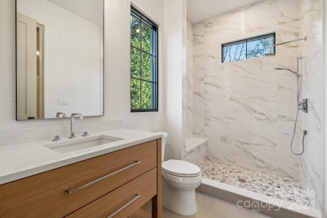 bathroom with vanity, toilet, and tiled shower