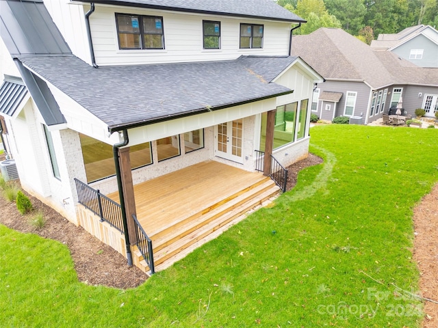 rear view of property with french doors, a wooden deck, and a lawn