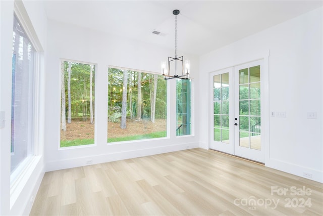 unfurnished sunroom with french doors and an inviting chandelier