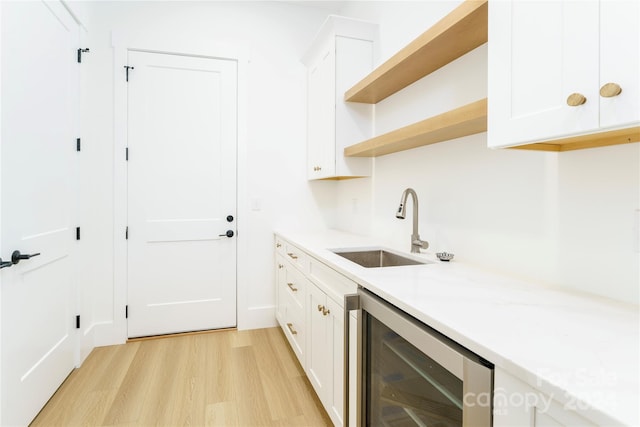 kitchen with wine cooler, sink, white cabinets, and light hardwood / wood-style floors