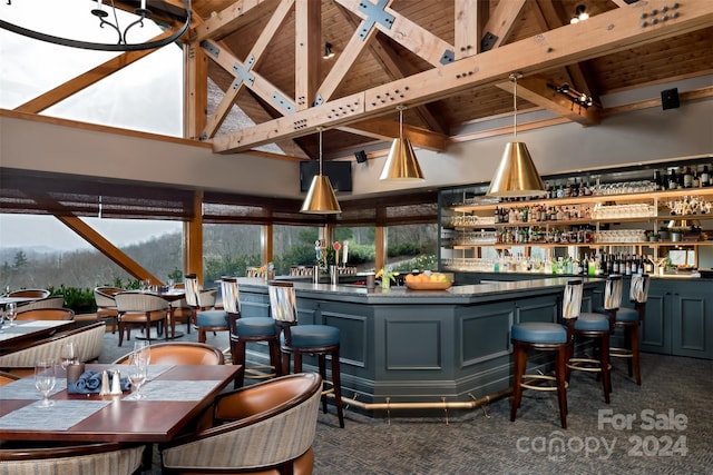 bar featuring decorative light fixtures, beam ceiling, high vaulted ceiling, a mountain view, and dark colored carpet