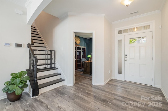 entryway with ornamental molding and wood-type flooring