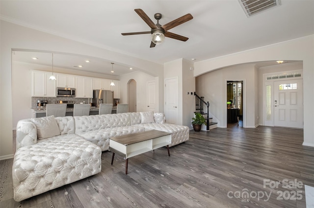 living room featuring ceiling fan, ornamental molding, and dark hardwood / wood-style flooring