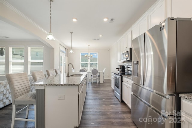 kitchen featuring sink, a kitchen island with sink, hanging light fixtures, stainless steel appliances, and light stone countertops