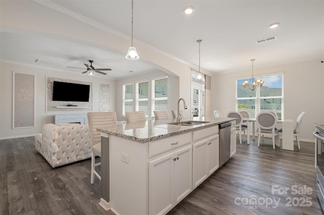 kitchen with decorative light fixtures, a center island with sink, appliances with stainless steel finishes, light stone countertops, and white cabinets