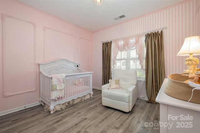 bedroom with wood-type flooring and a crib