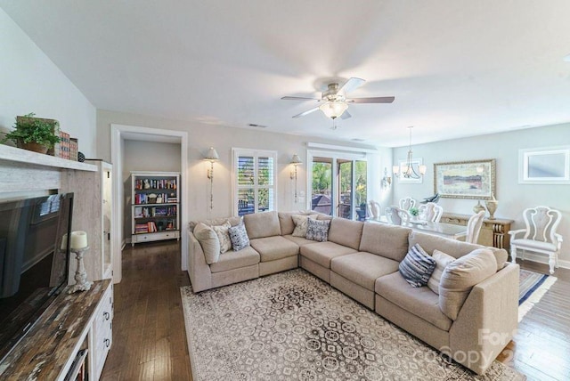 living room with dark wood-type flooring and ceiling fan with notable chandelier