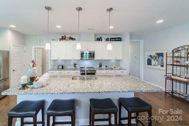 kitchen featuring decorative light fixtures, appliances with stainless steel finishes, and white cabinetry