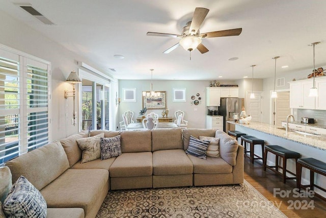 living room featuring wood-type flooring, sink, and ceiling fan with notable chandelier