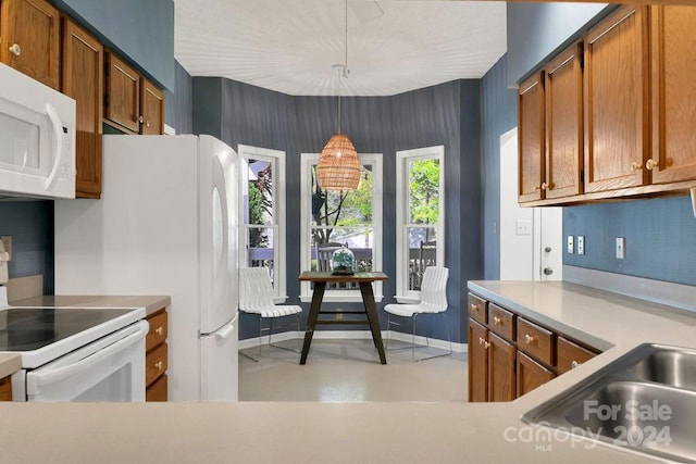 kitchen with hanging light fixtures, white appliances, tasteful backsplash, and sink