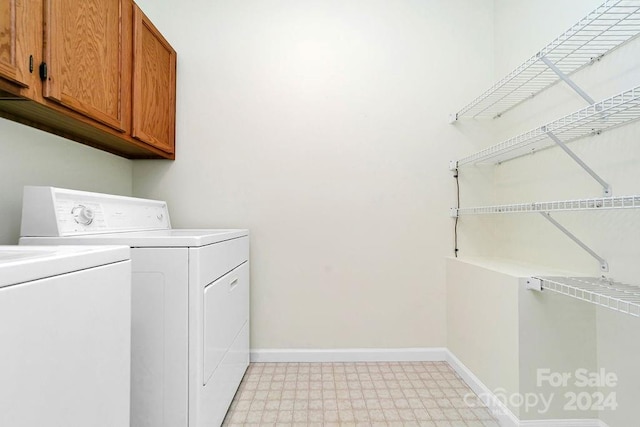 laundry room with light tile flooring, washer and dryer, and cabinets