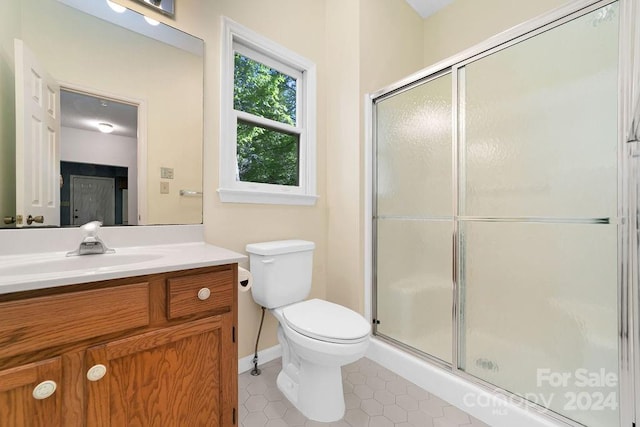 bathroom featuring a shower with door, tile floors, toilet, and oversized vanity