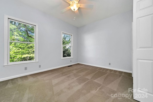 unfurnished room featuring ceiling fan, a wealth of natural light, and dark carpet