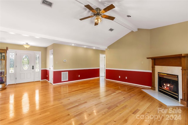 unfurnished living room with lofted ceiling with beams, a tiled fireplace, light hardwood / wood-style floors, and ceiling fan