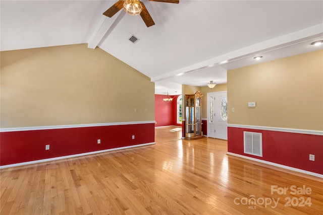 empty room with hardwood / wood-style flooring, lofted ceiling with beams, and ceiling fan