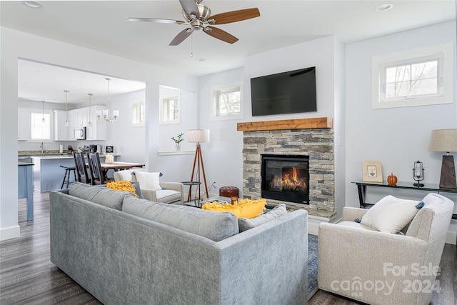 living room featuring dark hardwood / wood-style flooring, a healthy amount of sunlight, and a stone fireplace