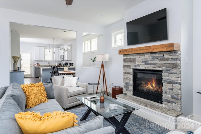 living room with hardwood / wood-style floors, a chandelier, and a stone fireplace