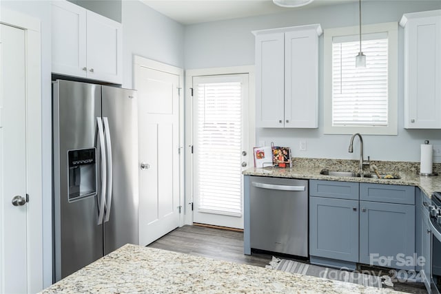 kitchen featuring a wealth of natural light, light hardwood / wood-style flooring, pendant lighting, and stainless steel appliances