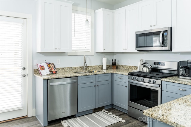 kitchen with hanging light fixtures, stainless steel appliances, white cabinetry, sink, and dark hardwood / wood-style flooring