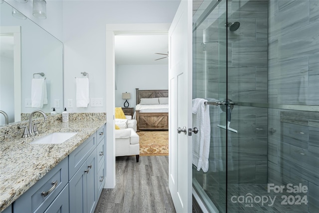 bathroom with hardwood / wood-style floors, a shower with shower door, and vanity with extensive cabinet space