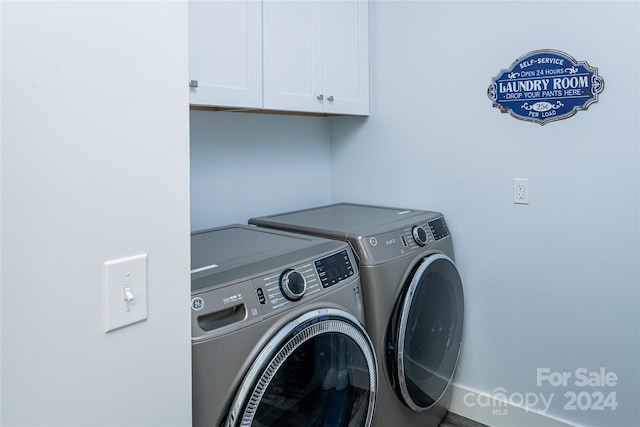 clothes washing area featuring washer and dryer and cabinets