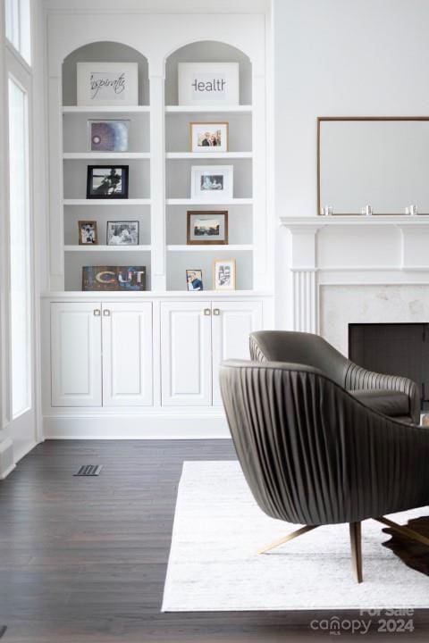 interior space featuring a high end fireplace, built in shelves, a wealth of natural light, and dark wood-type flooring