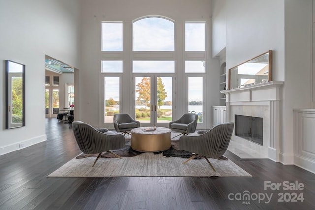 living room with dark hardwood / wood-style floors, a high end fireplace, a towering ceiling, and french doors