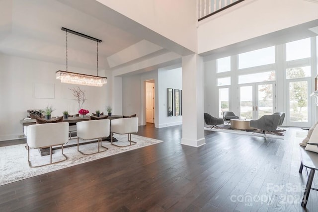 dining space with a high ceiling, dark wood-type flooring, and a notable chandelier