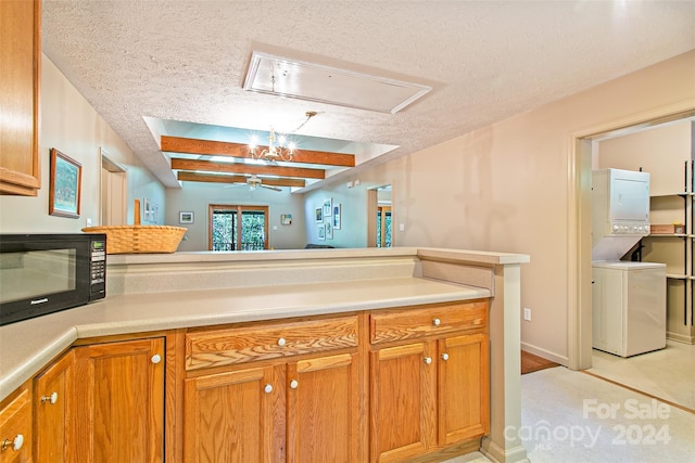 kitchen with beam ceiling, ceiling fan, stacked washer and dryer, and a textured ceiling