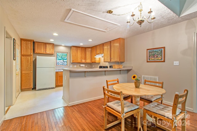 kitchen with a notable chandelier, white fridge, light tile floors, and a textured ceiling