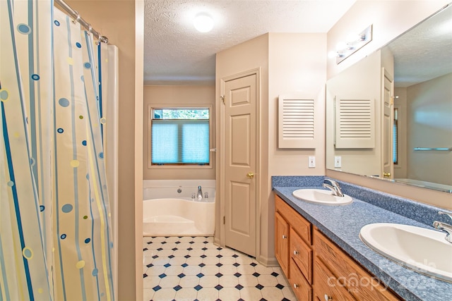 bathroom featuring double vanity, tile floors, a textured ceiling, and a tub