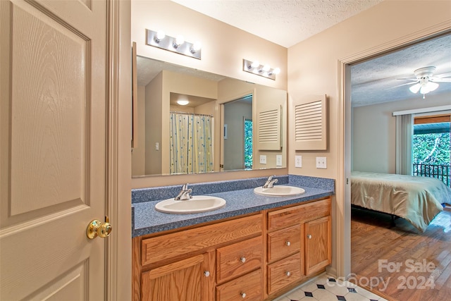 bathroom with oversized vanity, ceiling fan, tile flooring, a textured ceiling, and double sink