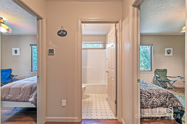 bedroom with tile flooring, a textured ceiling, and ensuite bathroom