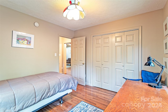 bedroom with wood-type flooring, a closet, and a textured ceiling