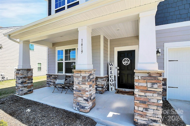 view of exterior entry featuring a garage and covered porch