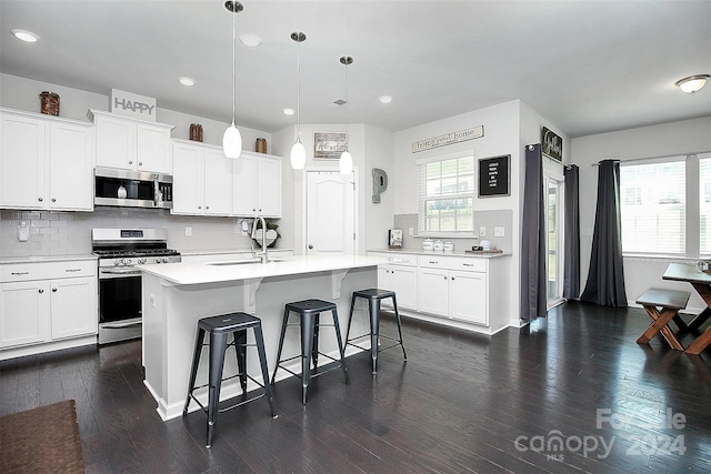 kitchen with sink, appliances with stainless steel finishes, a center island with sink, a wealth of natural light, and dark hardwood / wood-style flooring