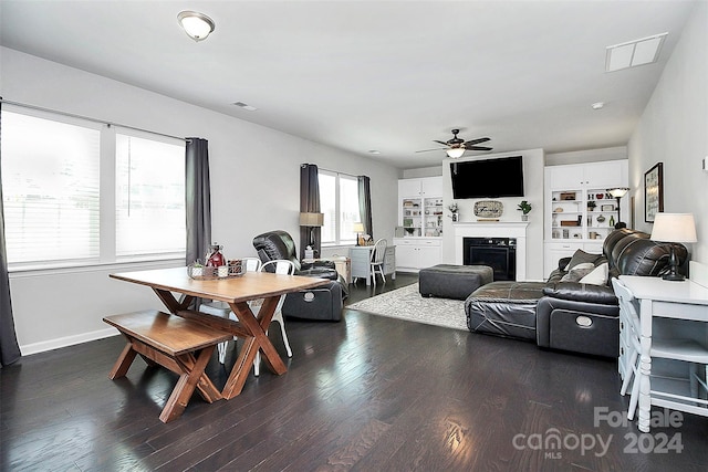 living room featuring built in features, ceiling fan, and dark wood-type flooring