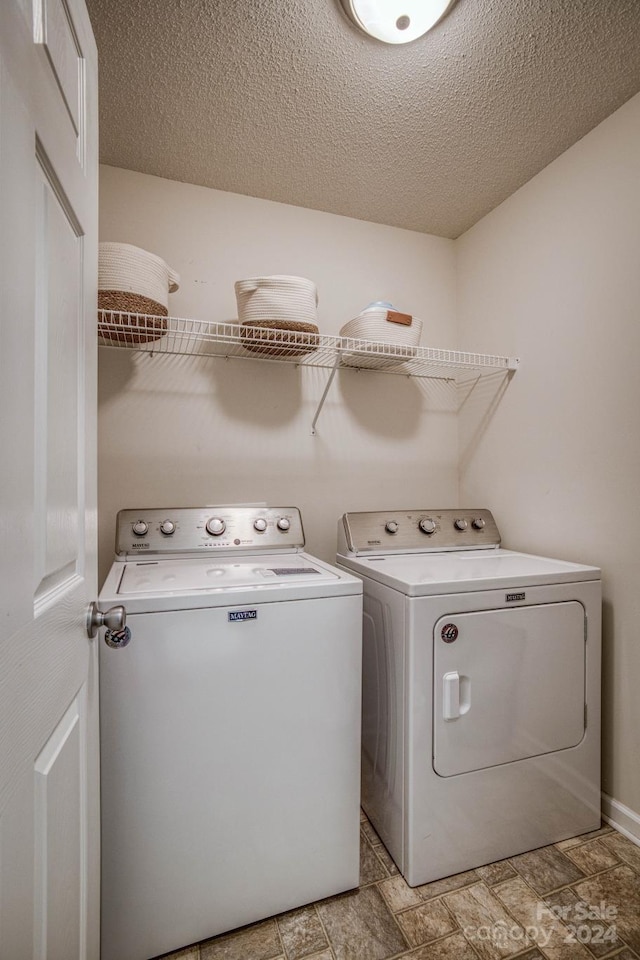 washroom with a textured ceiling, light tile floors, and washing machine and clothes dryer