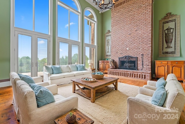 living room with a towering ceiling, french doors, a healthy amount of sunlight, and wood-type flooring