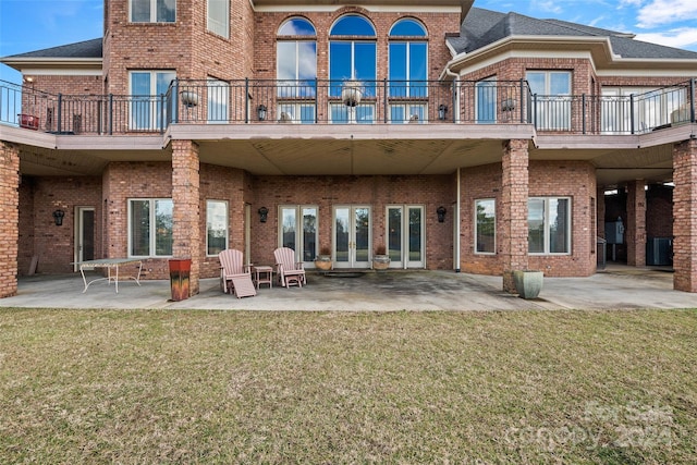 back of property with a yard, a patio, and a balcony