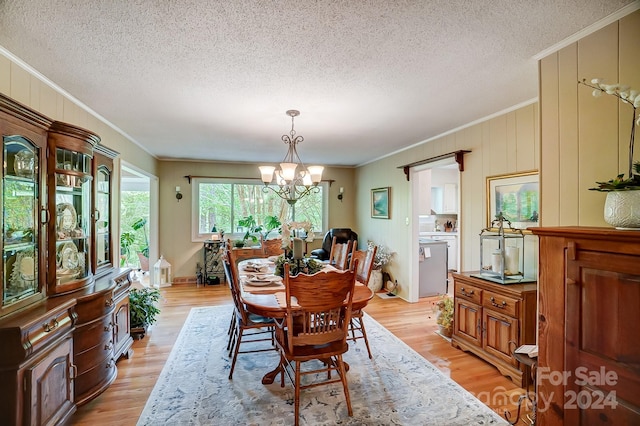 dining area with a notable chandelier, crown molding, light wood-type flooring, and a textured ceiling