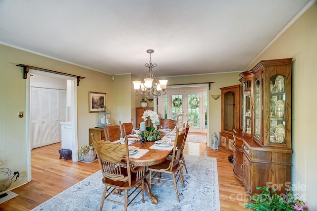 dining room featuring light hardwood / wood-style floors, ornamental molding, and an inviting chandelier