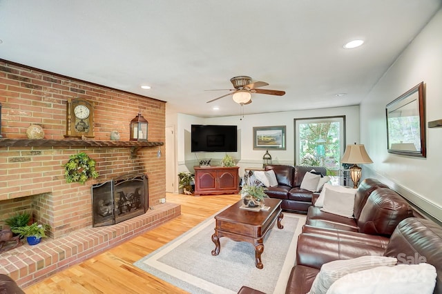 living room with brick wall, a brick fireplace, ceiling fan, and hardwood / wood-style floors